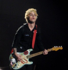 Ein weißer Mann mit blondierten Haaren und einer blauen Gitarre