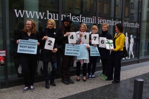 Sieben Personen stehen vor dem Frauenministerium, sie halten Plakate mit den Ziffern 24176 und dem Stapel Unterzeichnungen hoch.